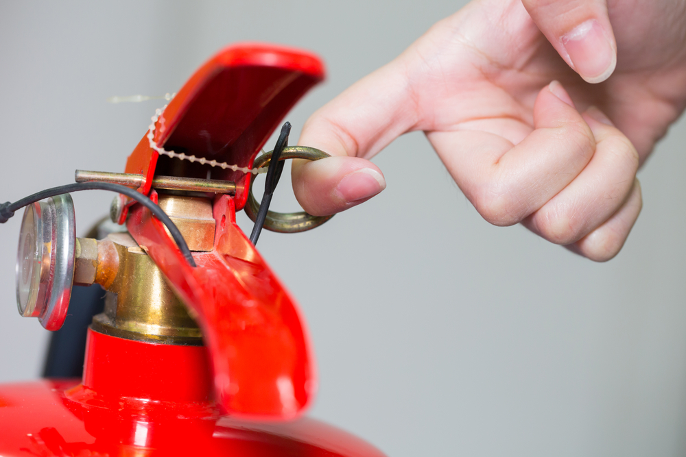 Close-,Up,Fire,Extinguisher,And,Pulling,Pin,On,Red,Tank.