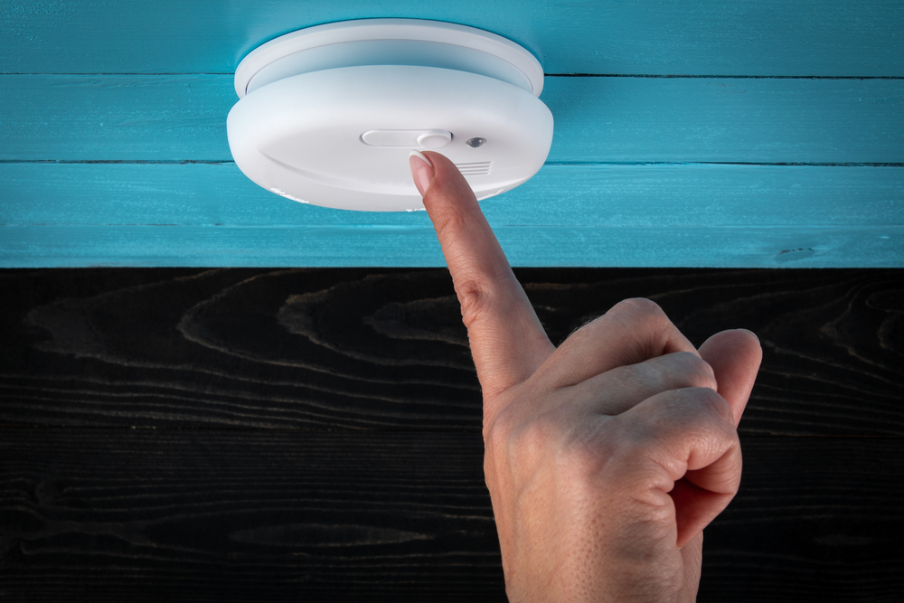 Close,Up,Smoke,Detector,On,A,Ceiling.,Woman's,Finger,Presses